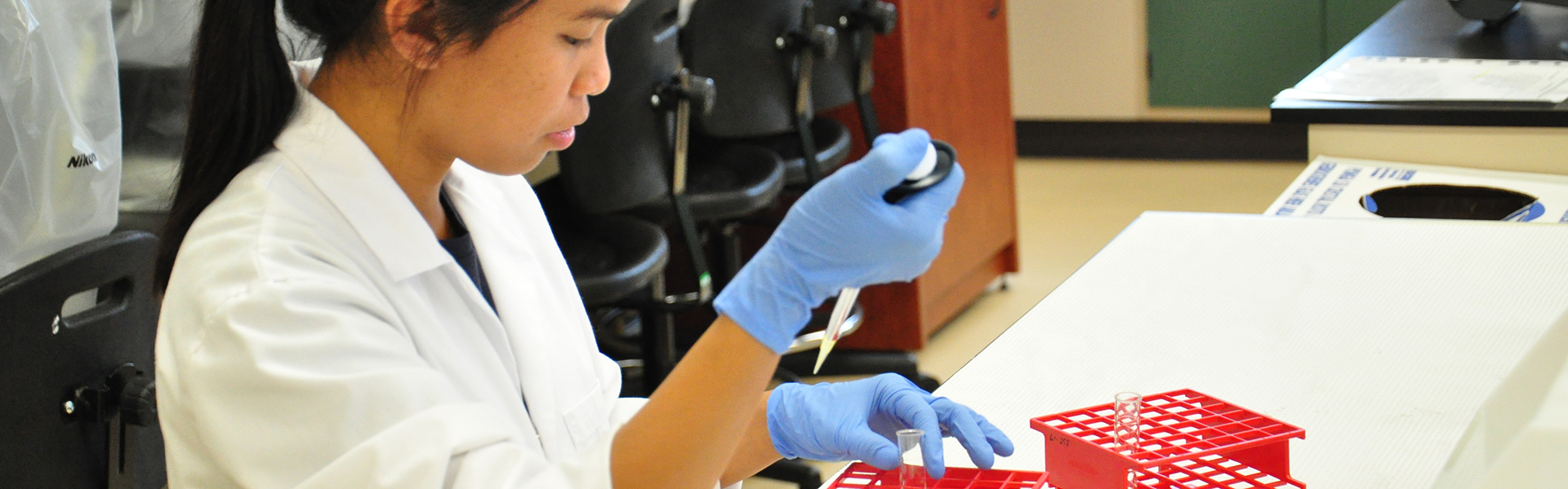 Étudiante en analyses biomédicales manipulant une pipette et une éprouvette en laboratoire